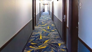 Un couloir d’hôtel avec un tapis à motifs et des portes de part et d’autre.