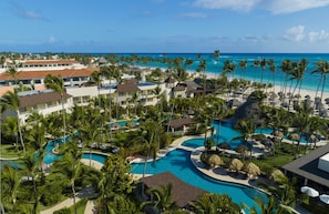 Un resort con varias piscinas, palmeras y vista al océano.