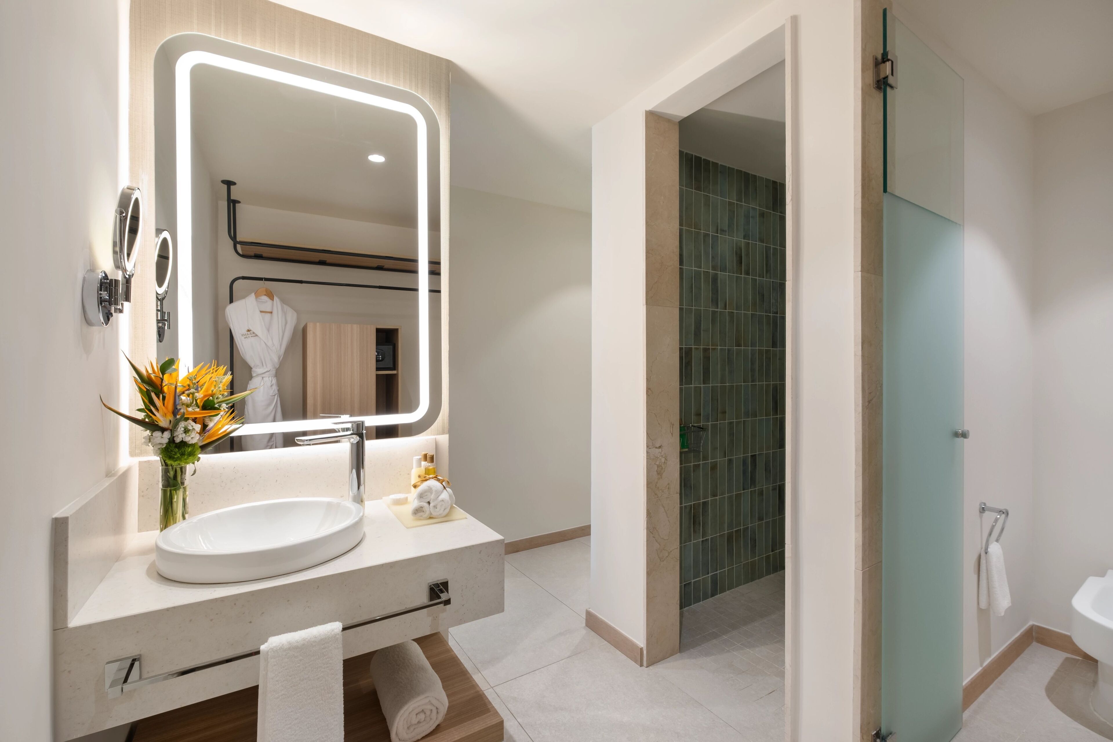 Un baño moderno con un espejo grande, un lavabo y una cabina de ducha de vidrio.