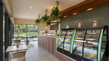 A modern cafe with a glass display case filled with pastries and a wooden counter with a menu board.