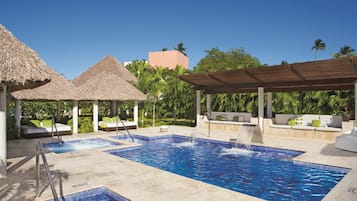 Un espace piscine comprenant un jacuzzi, des chaises longues et un coin salon abrité.