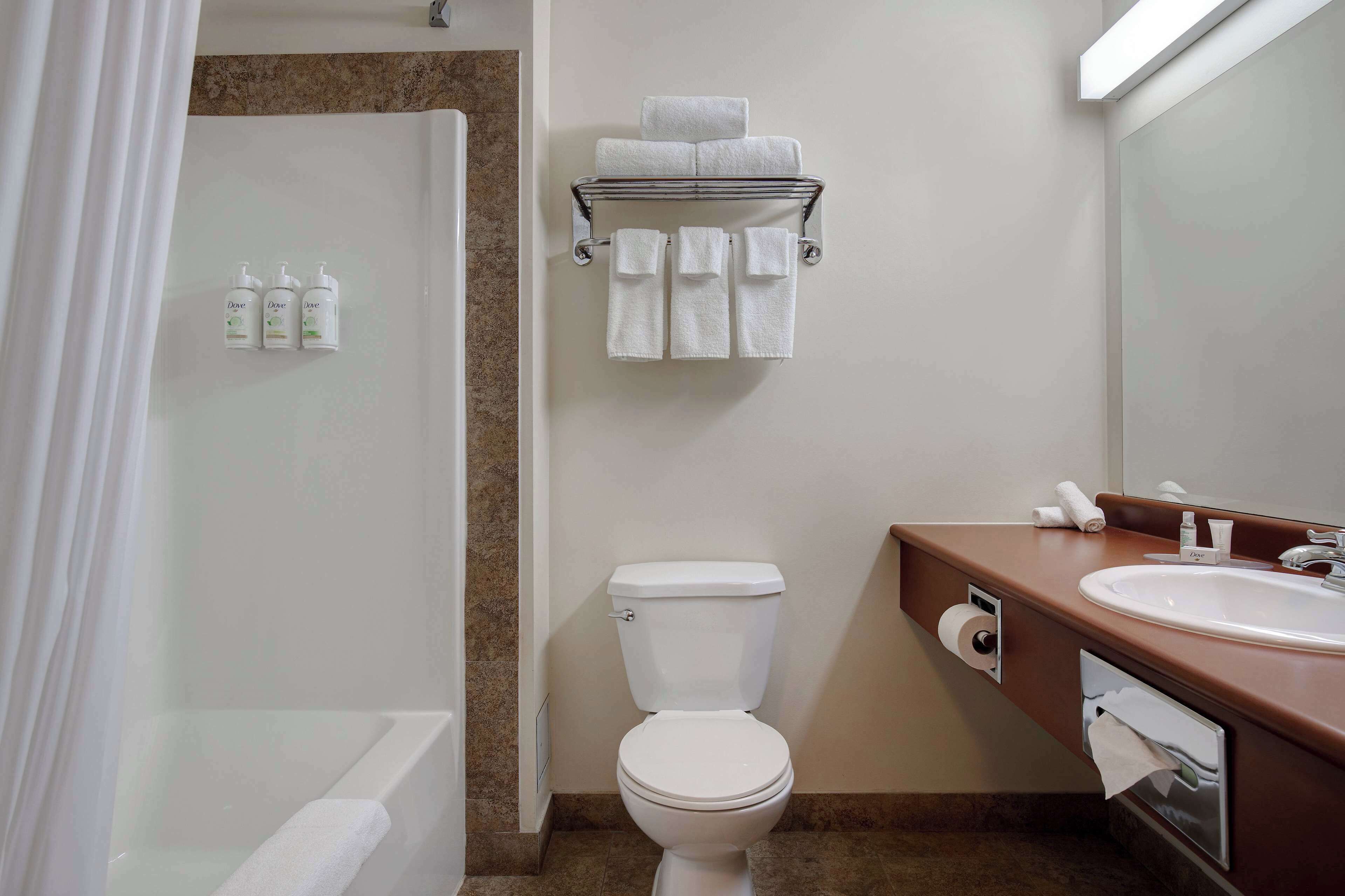 Un baño con bañera, inodoro, lavamanos y toallero.