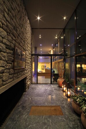 A stone wall with a framed picture, a marble floor, and a reception area with a desk and chairs. - Dioscouri Hotel (Sparta)