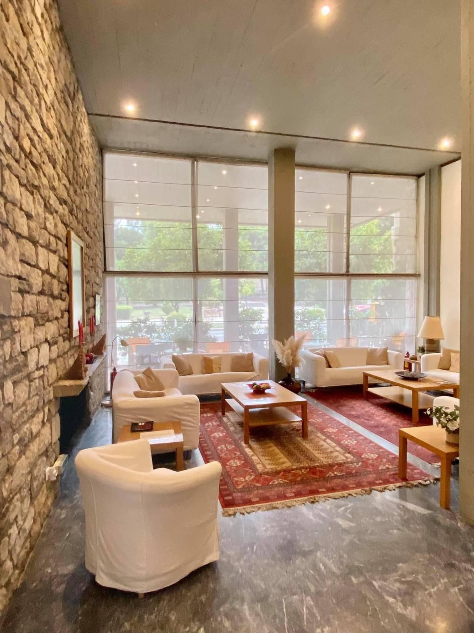 Amplia sala de estar con pared de piedra, ventanas grandes y diversas opciones de asiento.