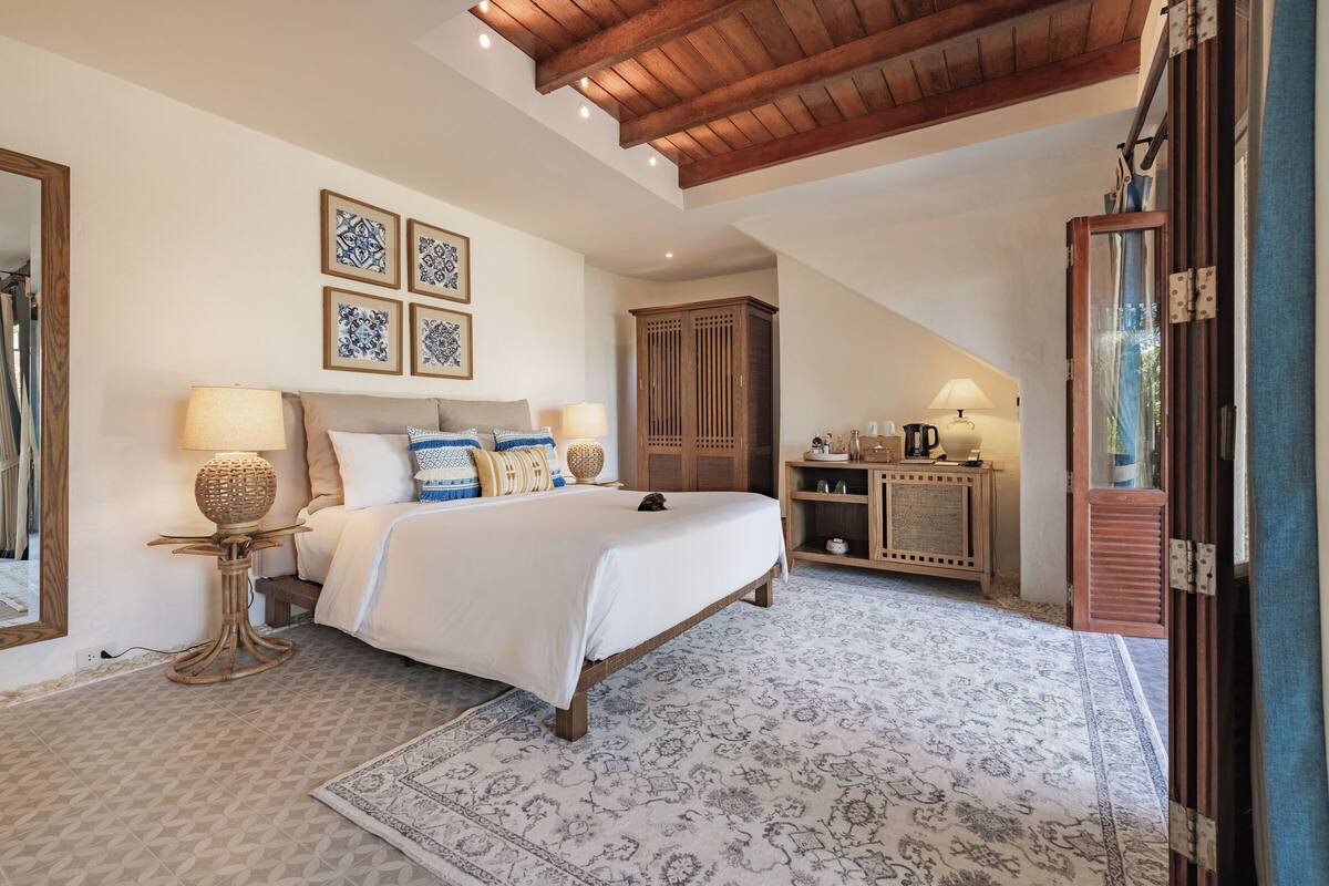 Un dormitorio con cama, mesitas de noche, armario y espejo.