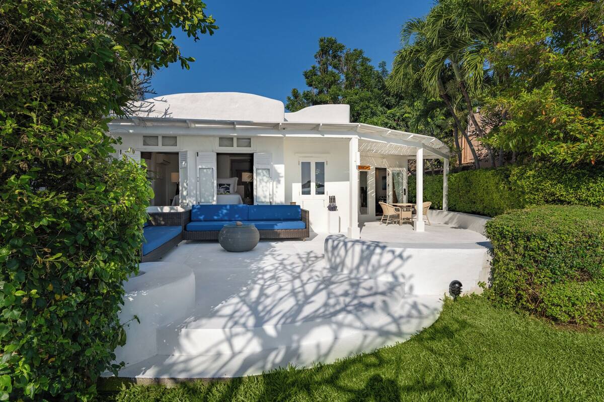 Una casa moderna con fachada blanca, un área de estar al aire libre en azul y un porche cubierto.