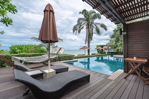 A wooden deck with wicker lounge chairs and a hammock, overlooking a pool and the ocean. - Aleenta Hua Hin - Pranburi (Pranburi)