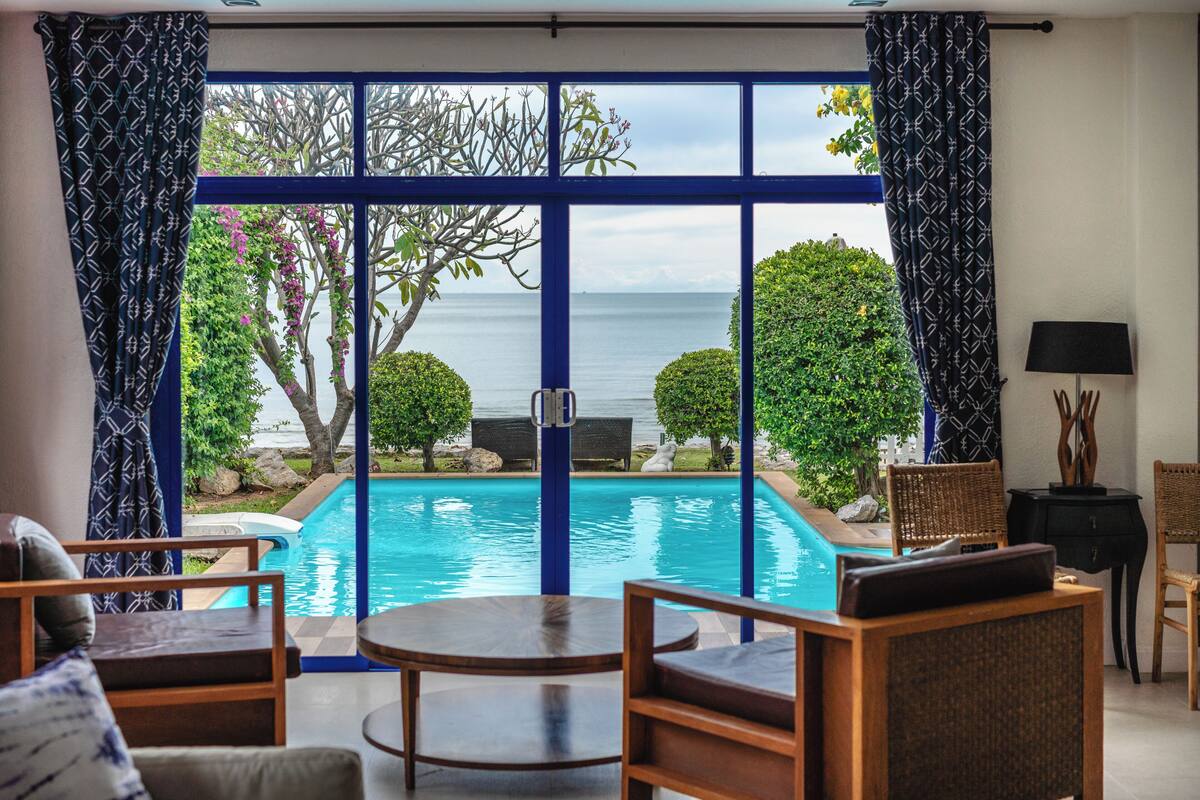 Una habitación con piscina, muebles de madera y vista al mar.