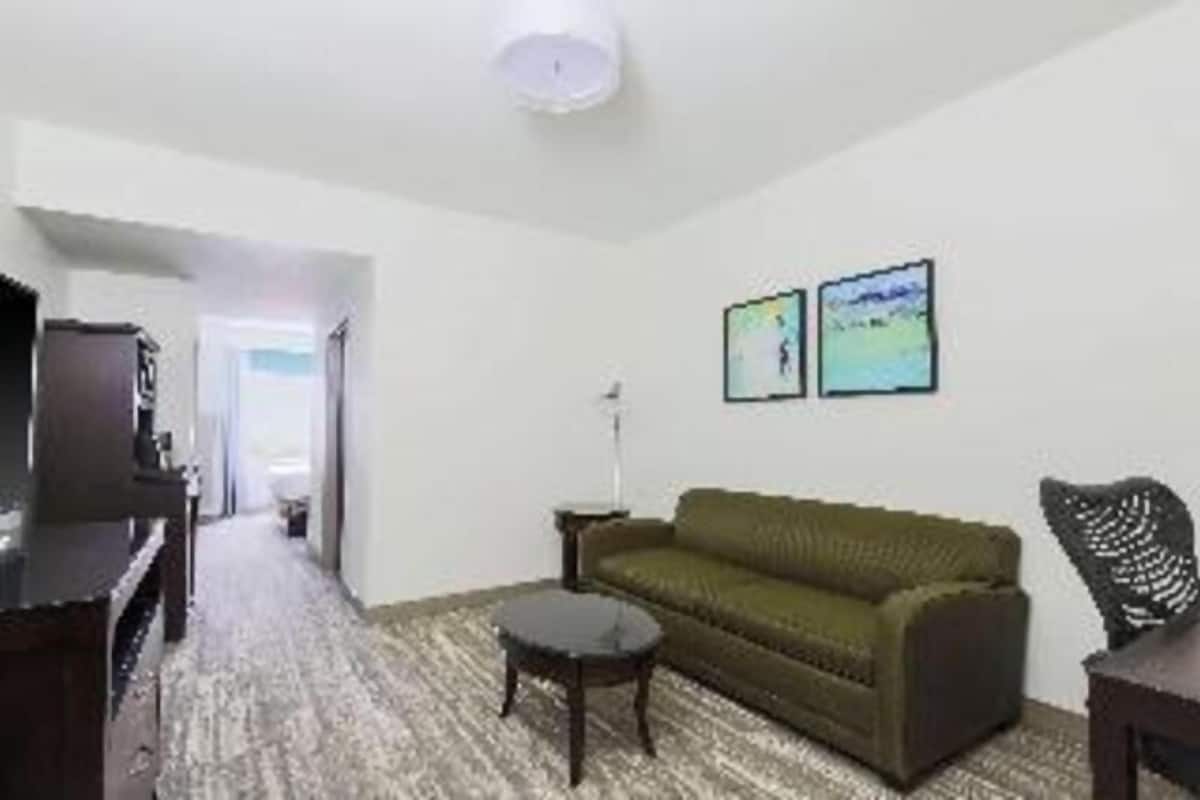 A room with a sofa, a small table, a lamp, and a television.