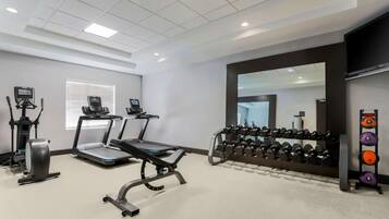A gym with treadmills, elliptical machines, and a rack of dumbbells.