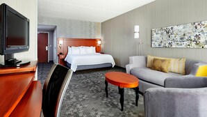 A hotel room with a bed, a sofa, a TV, a desk, and a painting on the wall. - Courtyard by Marriott Phoenix North/Happy Valley (Phoenix)