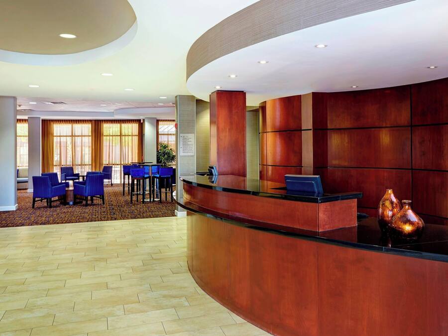 A hotel lobby with a curved reception desk, blue seating area, and large windows.