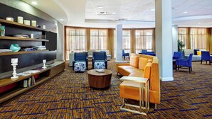 A modern hotel lobby with a patterned carpet, seating areas, and a bookshelf. - Courtyard by Marriott Phoenix North/Happy Valley (Phoenix)