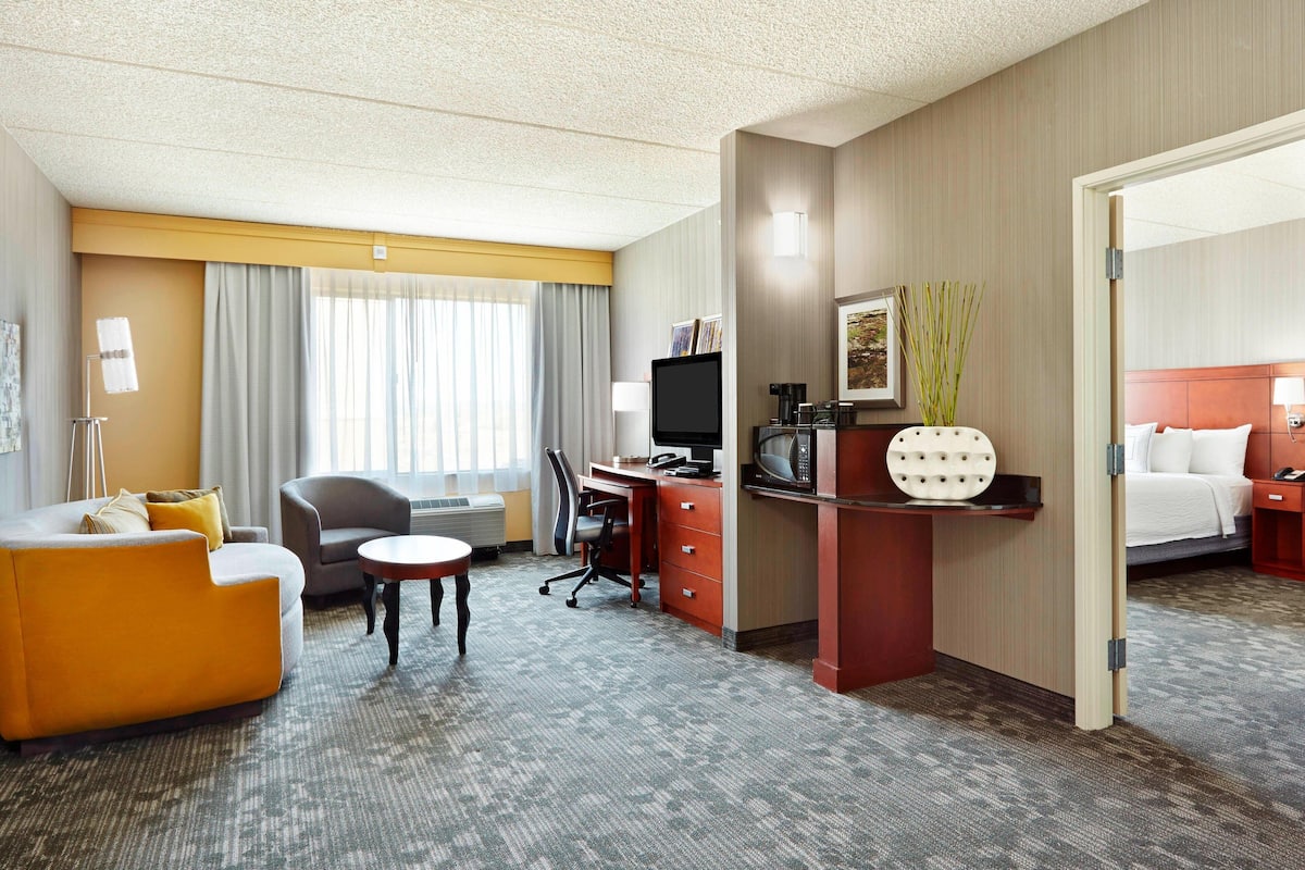 Habitación de hotel con sofá, escritorio, silla, cama y una mesita.
