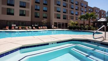 A hotel pool area with lounge chairs and a building in the background.