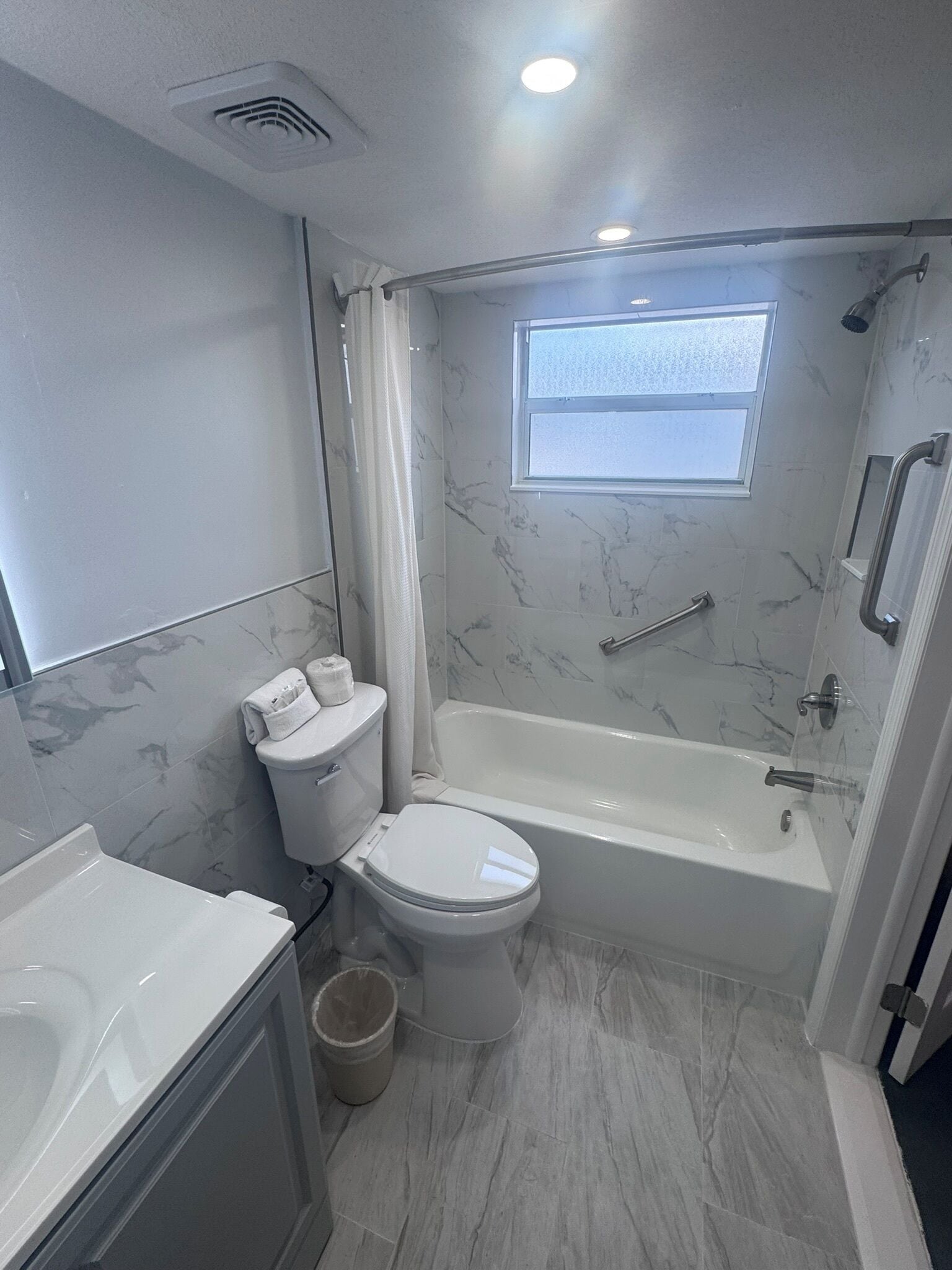 A bathroom with a bathtub, toilet, and a window.
