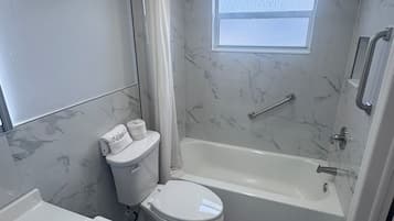 Ein Badezimmer mit Badewanne, Toilette und einem Fenster.