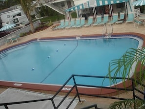 A swimming pool with lounge chairs and a covered seating area. - Belleair Village Motel (Largo)