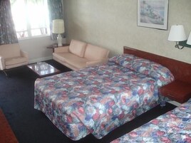 A hotel room with a bed, a sofa, a small table, and two lamps.