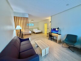 Una sala de estar moderna con un sofá, un escritorio con una computadora, un televisor y una silla.