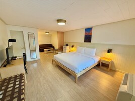 Habitación de hotel con cama, mesitas de noche, escritorio, silla, espejo y un cuadro en la pared.