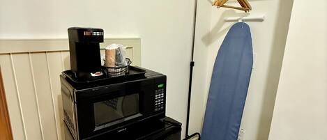 Una kitchenette compacta con microondas y un refrigerador pequeño.