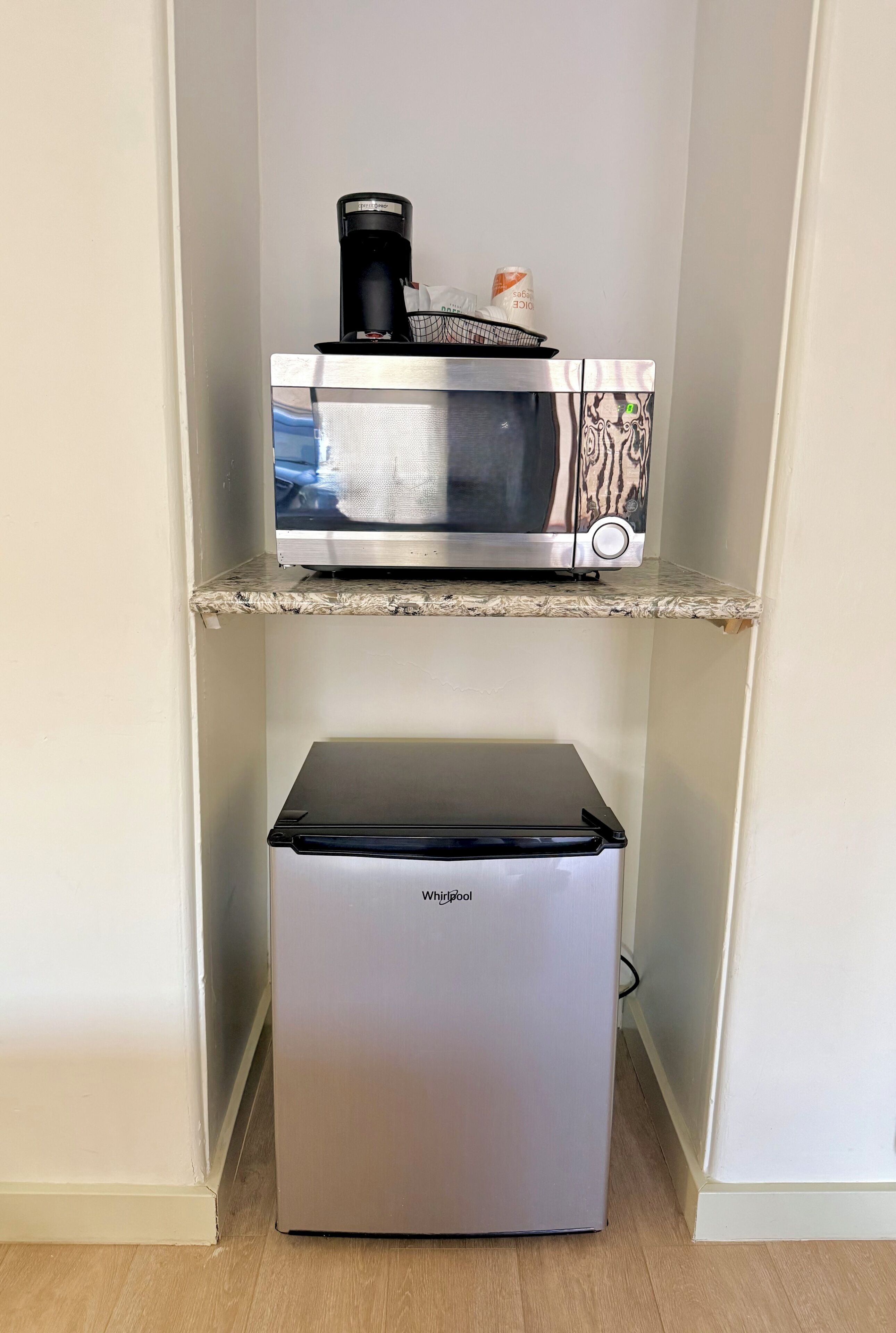 A compact kitchen with a microwave on the upper shelf and a refrigerator below.