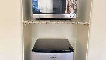 A compact kitchen with a microwave on the upper shelf and a refrigerator below.