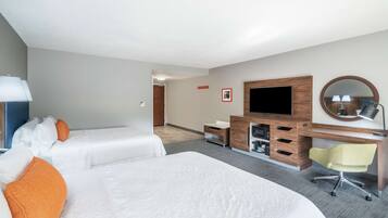 A hotel room with two beds, a desk, a TV, and a mirror.