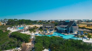 A resort with multiple swimming pools, a large building with a balcony, and a surrounding landscaped area. - WaterSound Inn (Santa Rosa Beach)