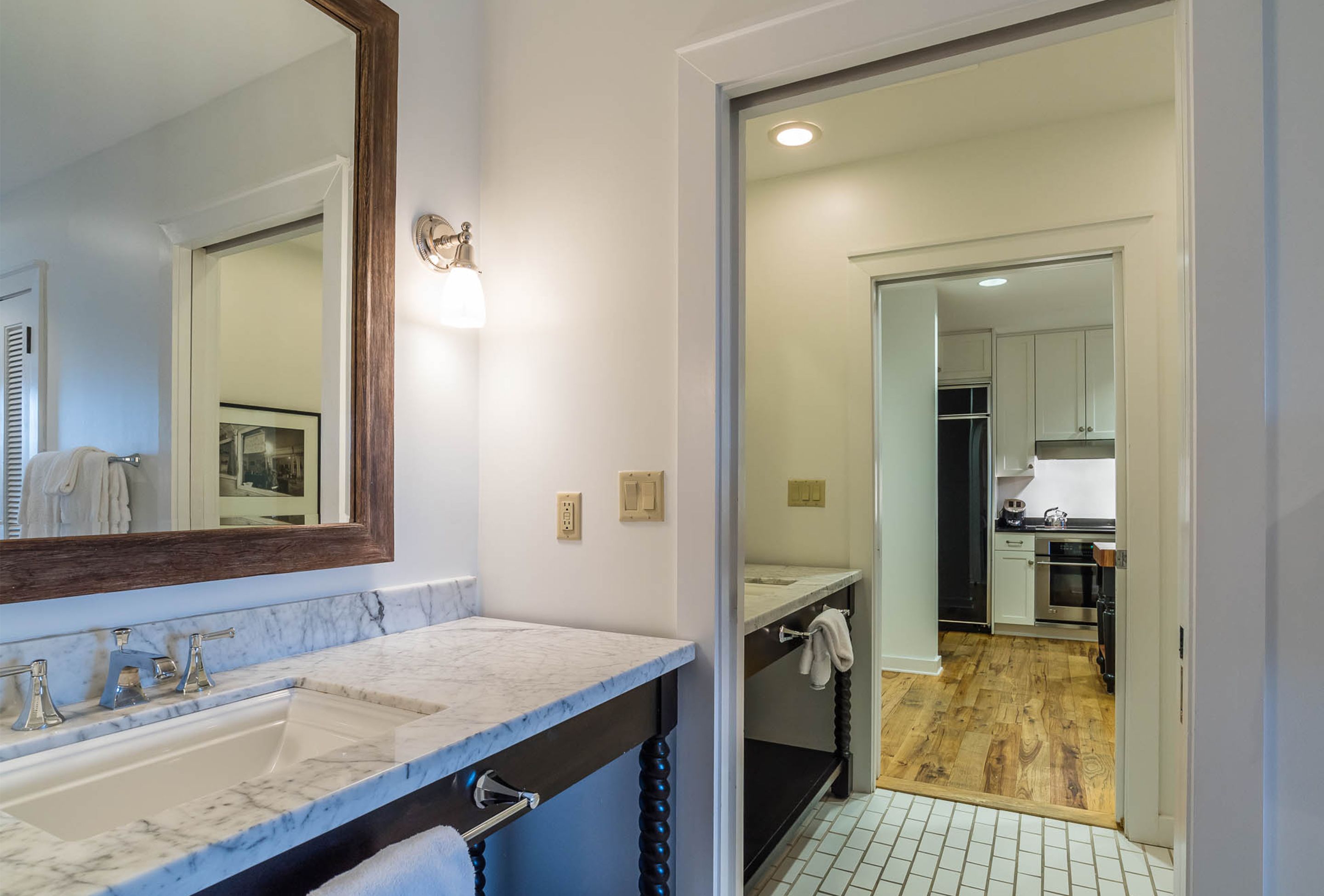 A bathroom with a marble sink, a large mirror, and a towel hanging on the wall.