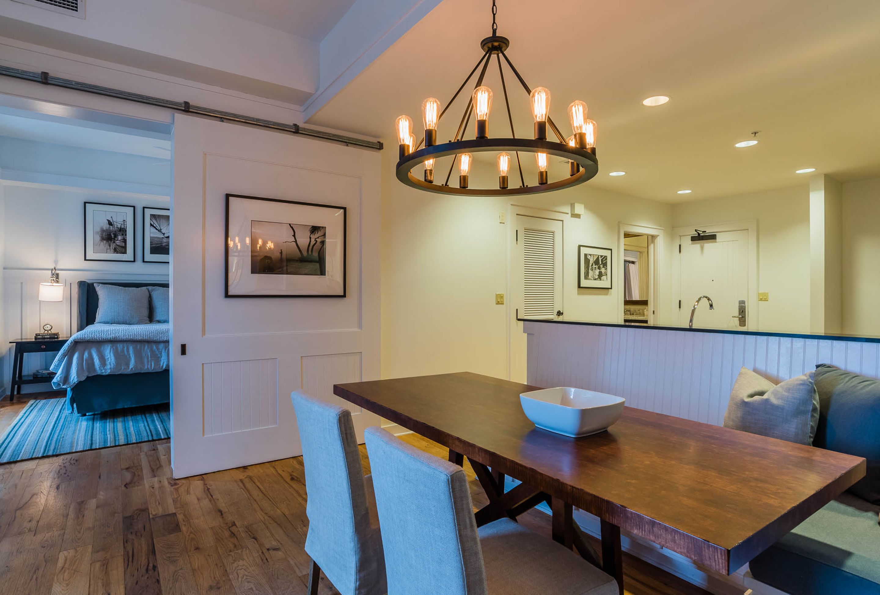 Un comedor con una mesa de madera, sillas y un cuenco. Un candelabro cuelga sobre la mesa.
