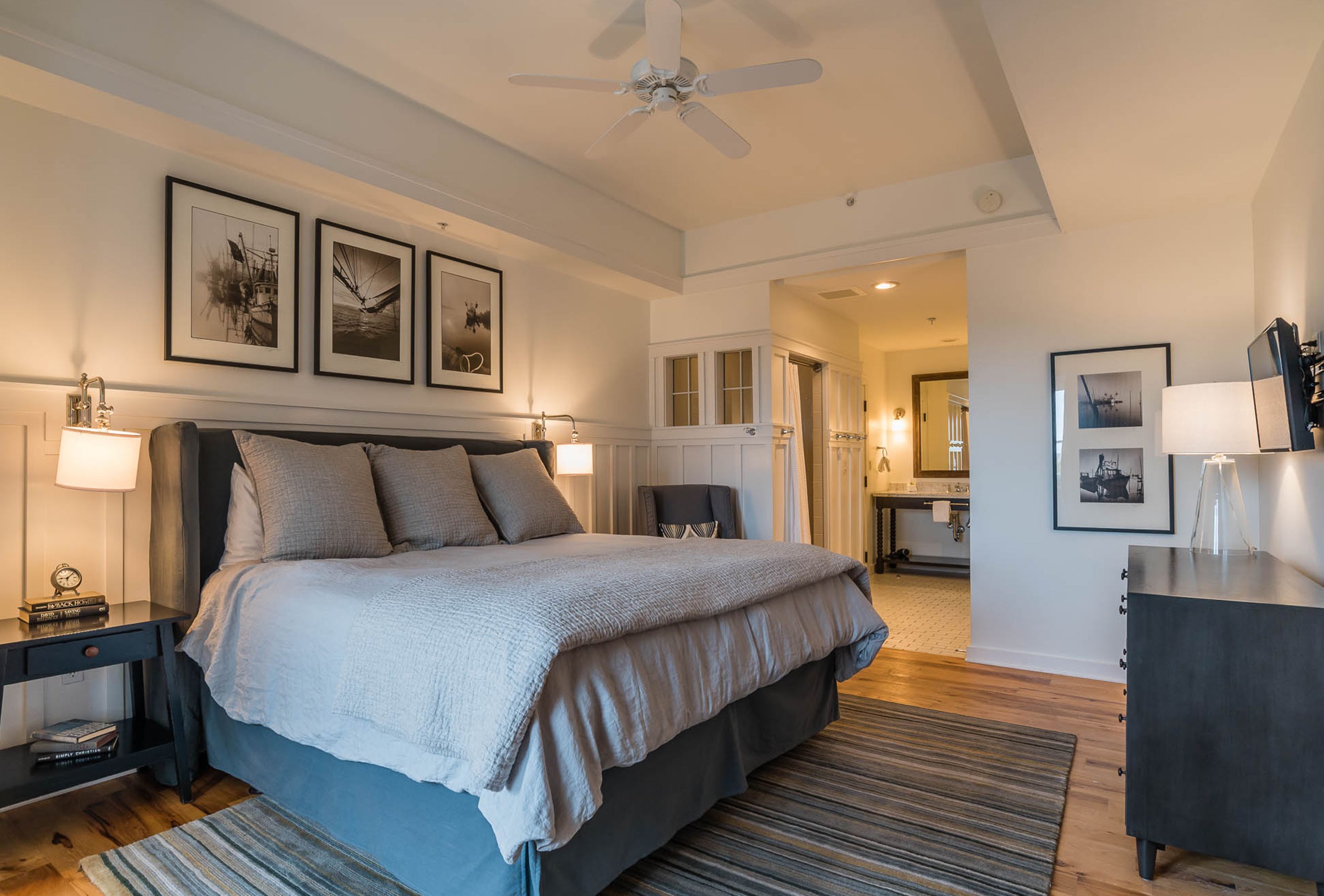 Una camera da letto moderna con un letto grande, una ventola a soffitto e opere d'arte incorniciate al muro.