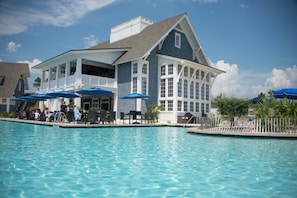 A large pool with a covered patio area, lounge chairs, and umbrellas. - WaterSound Inn (Santa Rosa Beach)