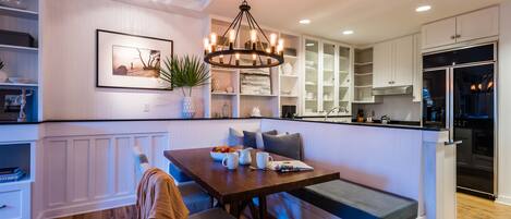 A modern kitchen with a built-in bench, wooden flooring, and white cabinetry.