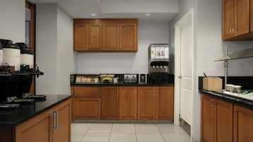 A modern kitchen with wooden cabinets, a black countertop, and various appliances including a coffee maker and toaster.