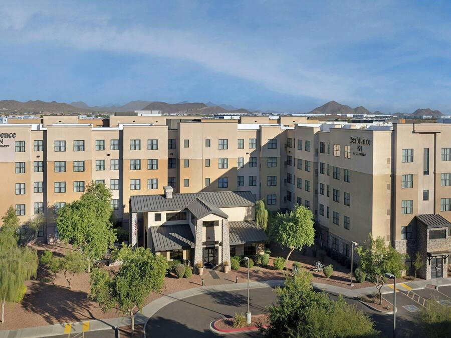 A hotel with multiple buildings, a parking area, and a mountainous backdrop.