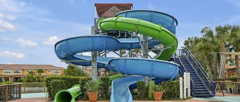 A water park with multiple slides, a pool, and a building with a red roof.