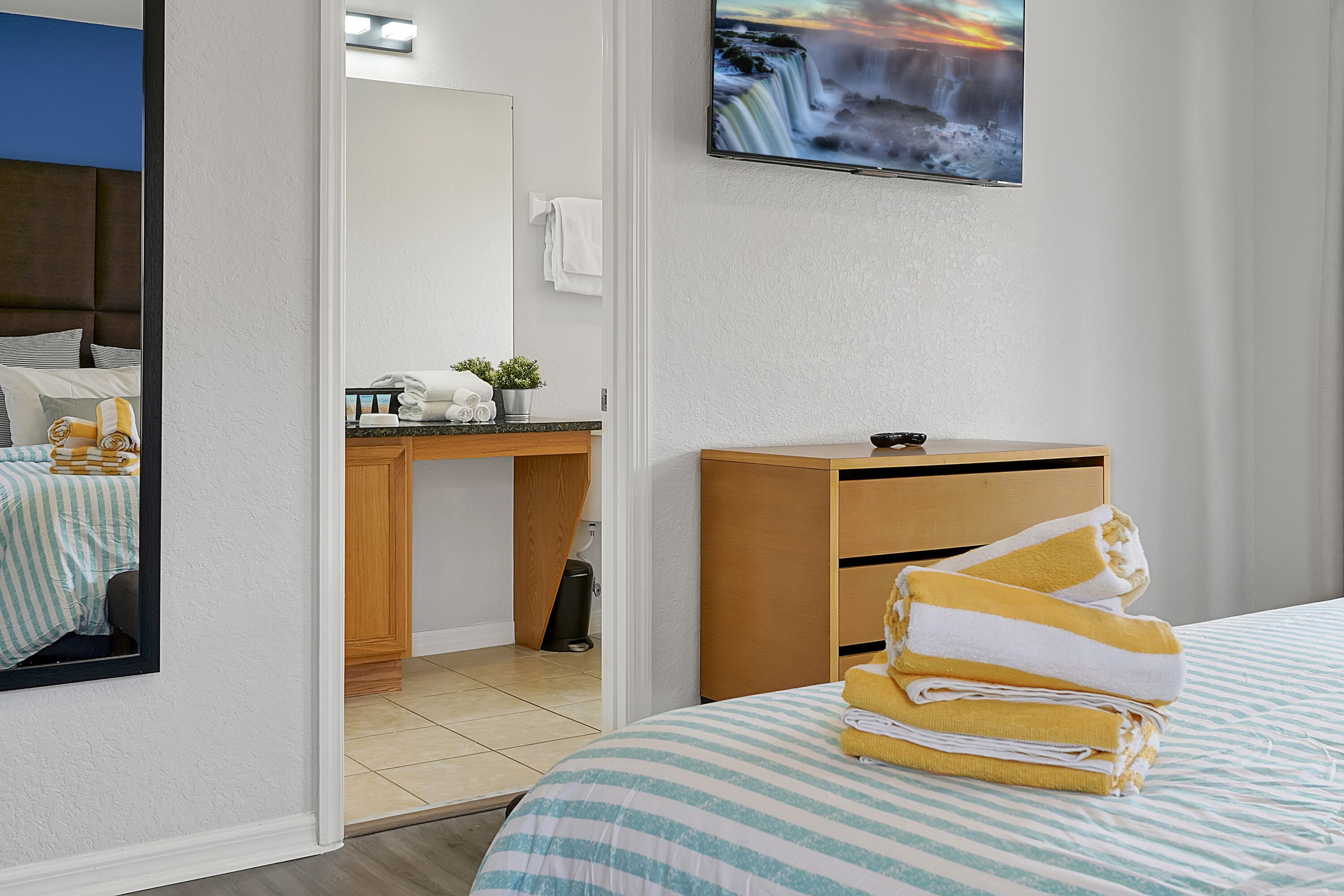 A hotel room with a bed, a desk, a TV, and a bathroom.