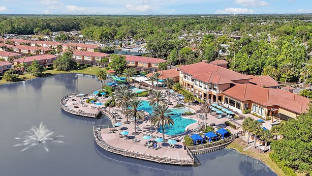 A resort with a large central pool, multiple guest villas, and a scenic view of the surrounding landscape.