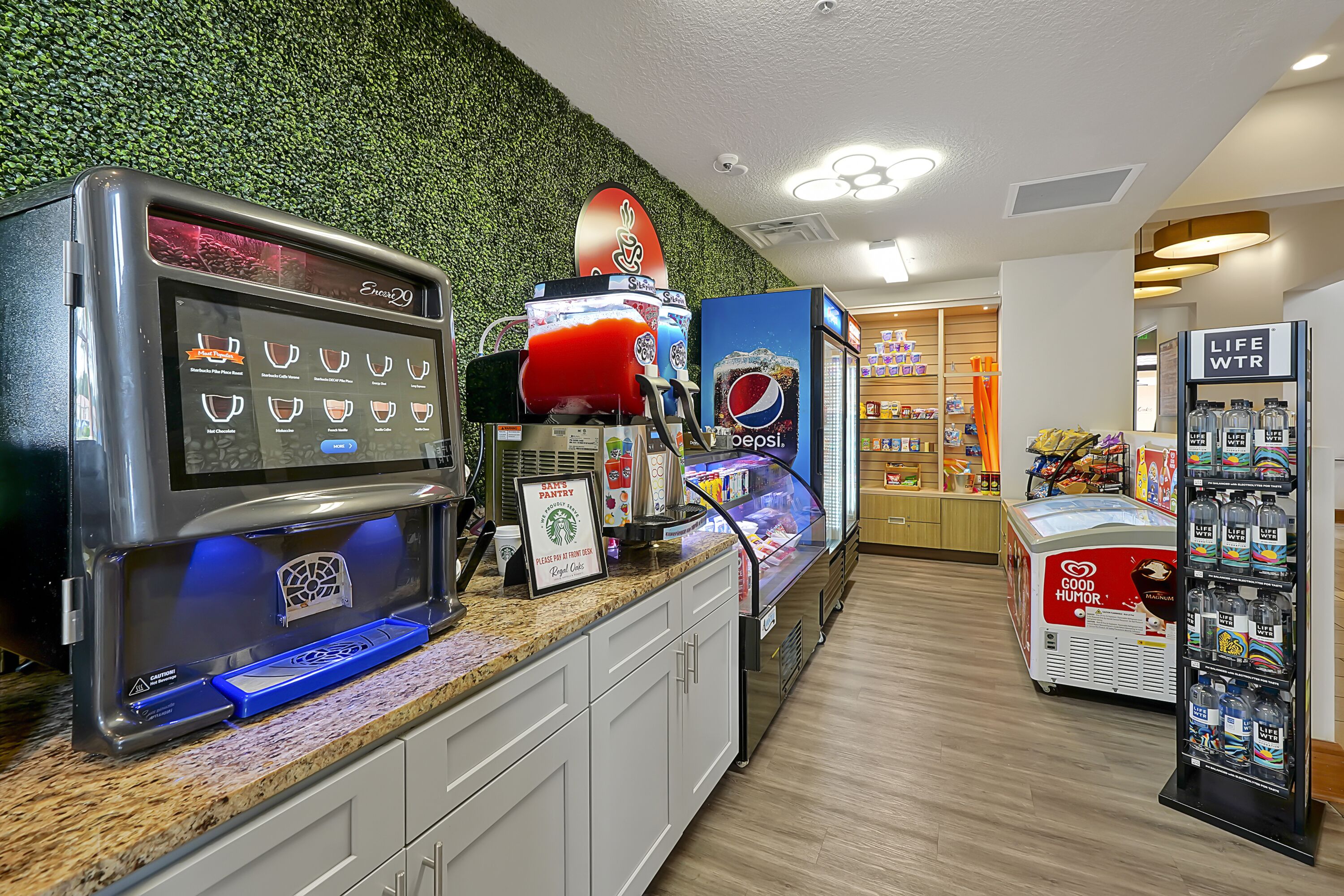 Un espace de libre-service proposant une variété de boissons, un panneau Starbucks et un présentoir Pepsi.