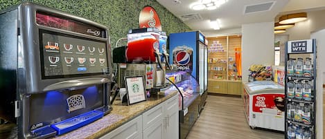 Un espace de libre-service proposant une variété de boissons, un panneau Starbucks et un présentoir Pepsi.