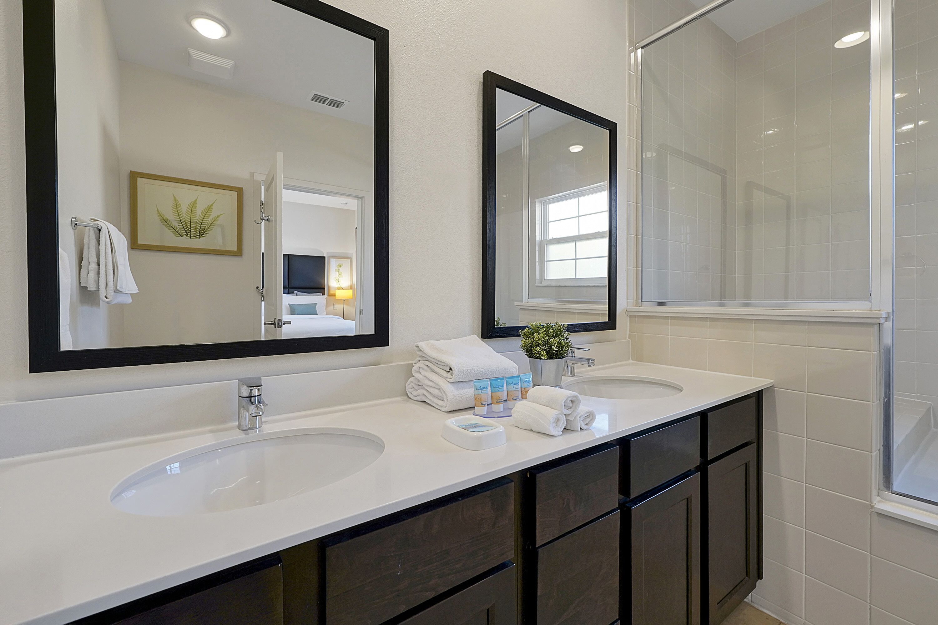 A bathroom with two sinks, dark cabinets, and a large mirror.