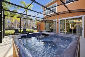 A hot tub in a covered outdoor area with a view of neighboring houses. - Regal Oaks Resort Vacation Townhomes by IDILIQ (Kissimmee)
