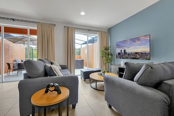 A hotel room with a large bed, a bedside table, a mirror, a window with curtains, and a view of the outside balcony. at Regal Oaks Resort Vacation Townhomes by IDILIQ