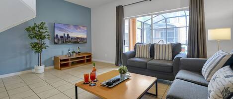 Una sala de estar moderna con un sofá, una mesa de centro, un televisor y un cuadro de un paisaje urbano en la pared.