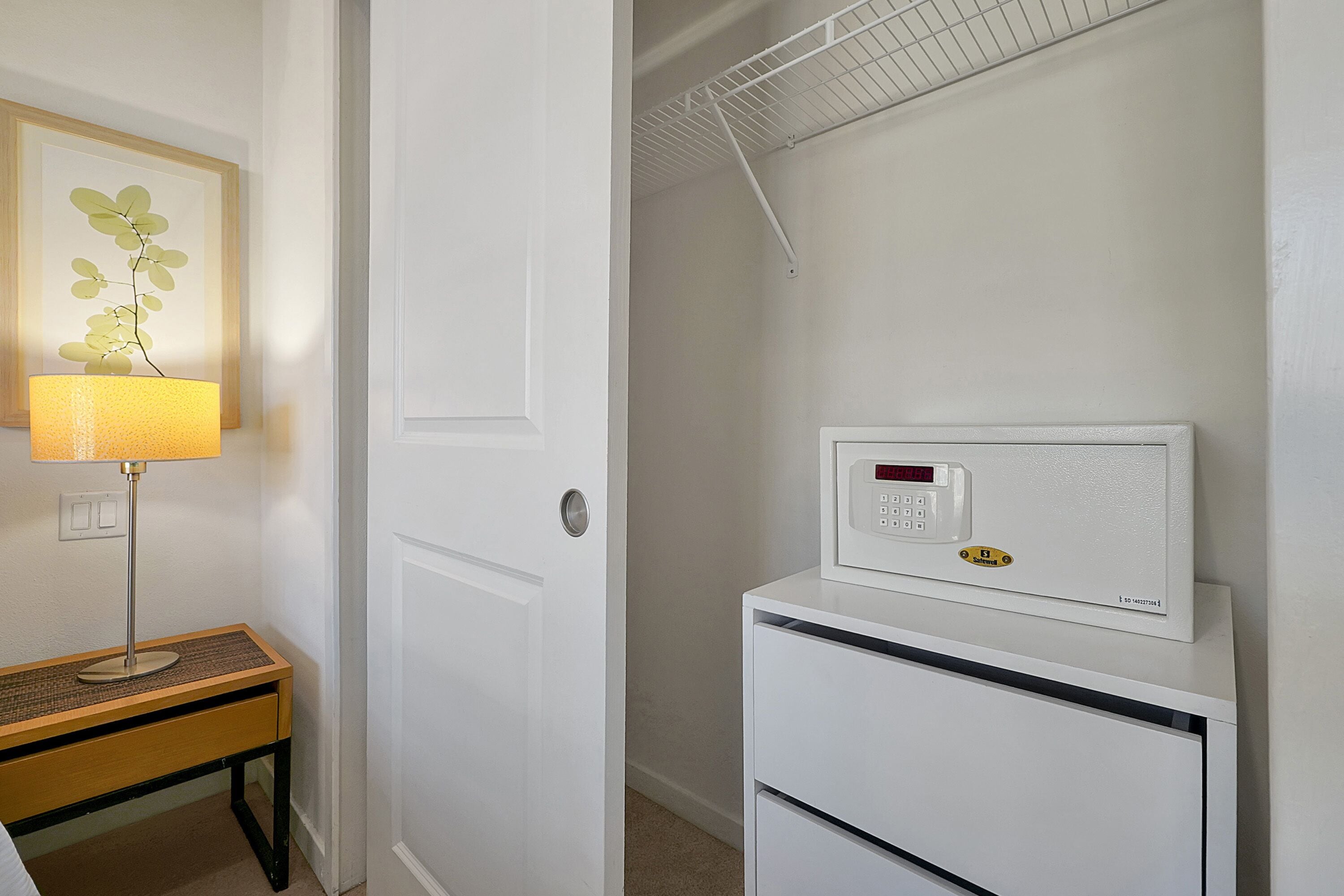 A white door, a white thermostat, and a lamp on a wooden table.