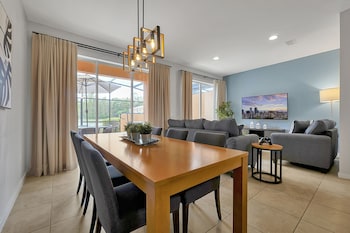 A restaurant with a view of palm trees and a pool. It features wooden tables and chairs, and large windows. at Regal Oaks Resort Vacation Townhomes by IDILIQ