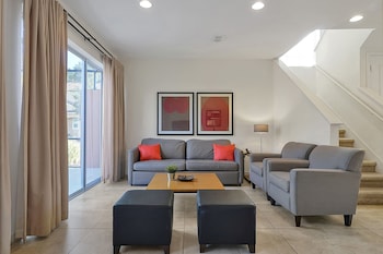 A modern living room with a grey sofa, a wooden coffee table, and a dining area with a kitchen in the background. at Regal Oaks Resort Vacation Townhomes by IDILIQ