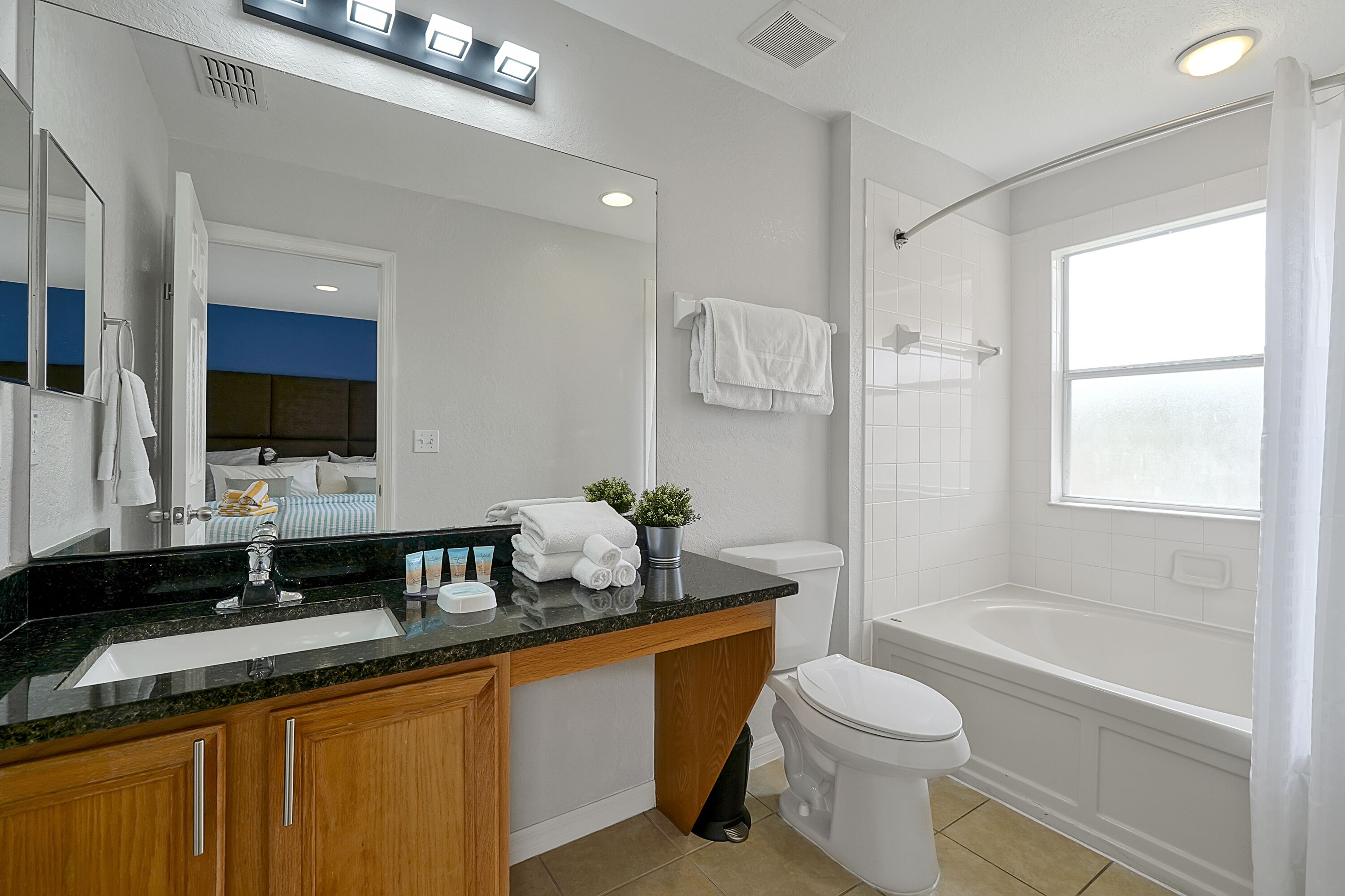 A modern bathroom with a sink, mirror, toilet, and bathtub.
